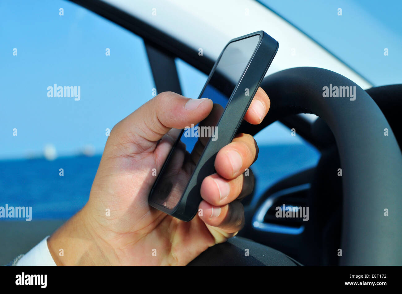 Primo piano di un uomo utilizzando uno smartphone durante la guida di una vettura Foto Stock