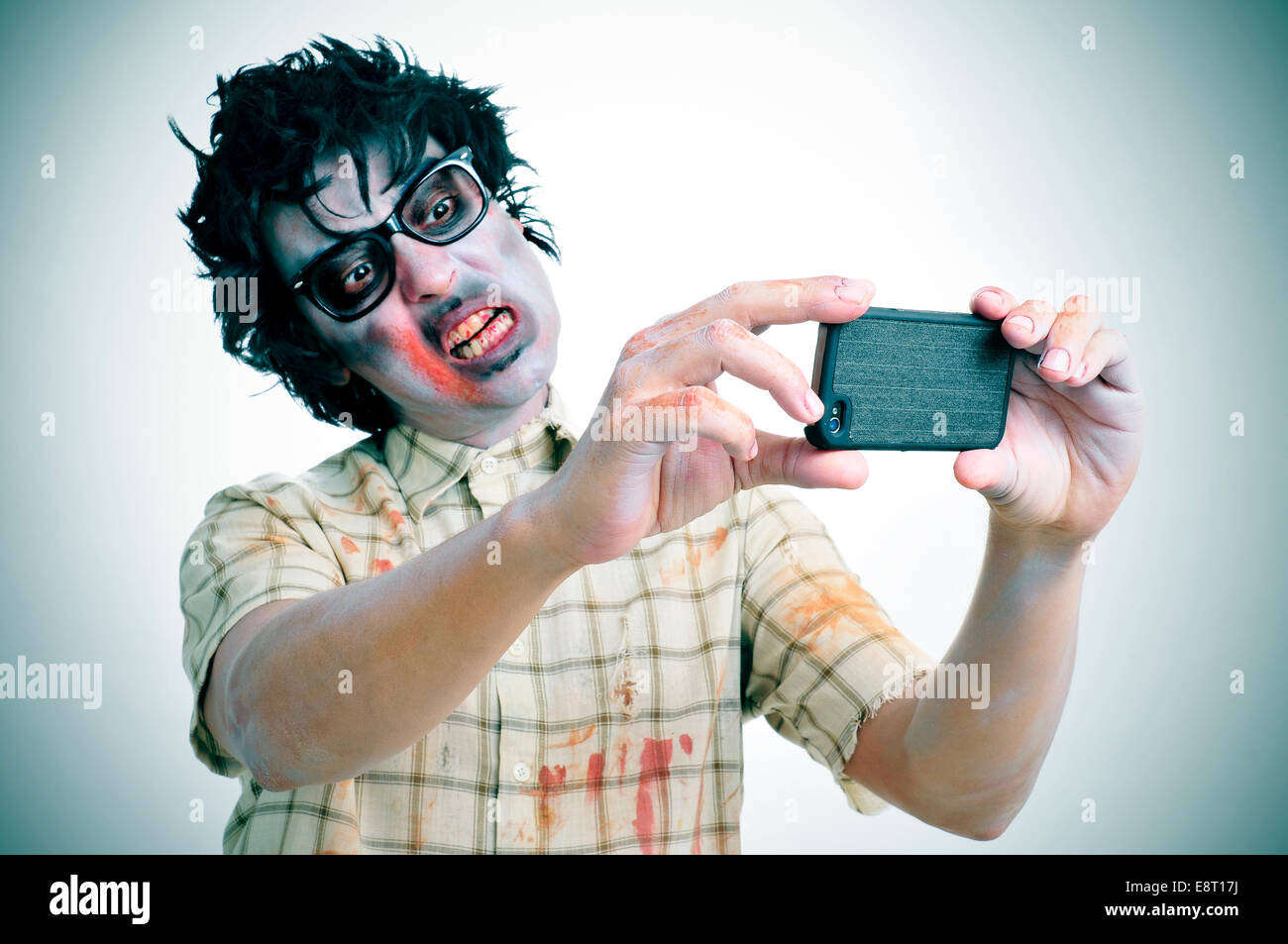 Un pauroso zombie prendendo un selfie di se stesso con uno smartphone, con un effetto di filtro Foto Stock