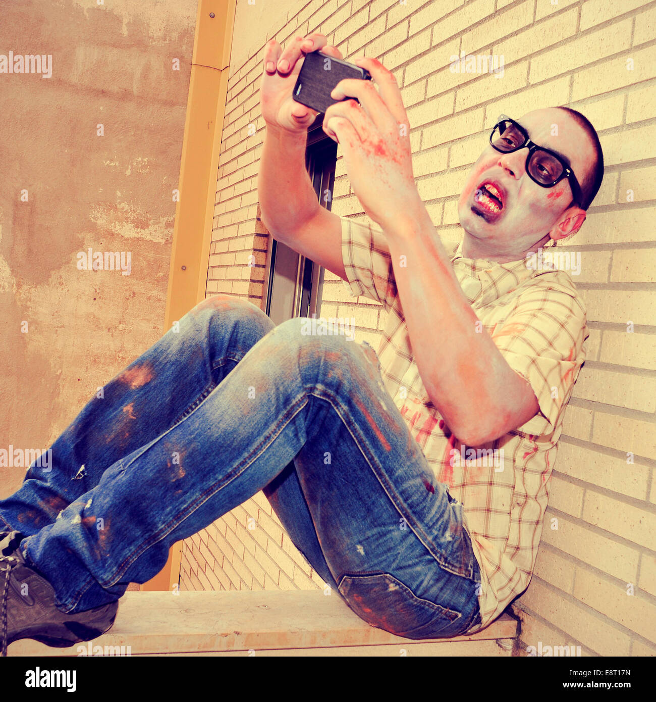 Un pauroso zombie prendendo un selfie di se stesso con uno smartphone, con un effetto retrò Foto Stock