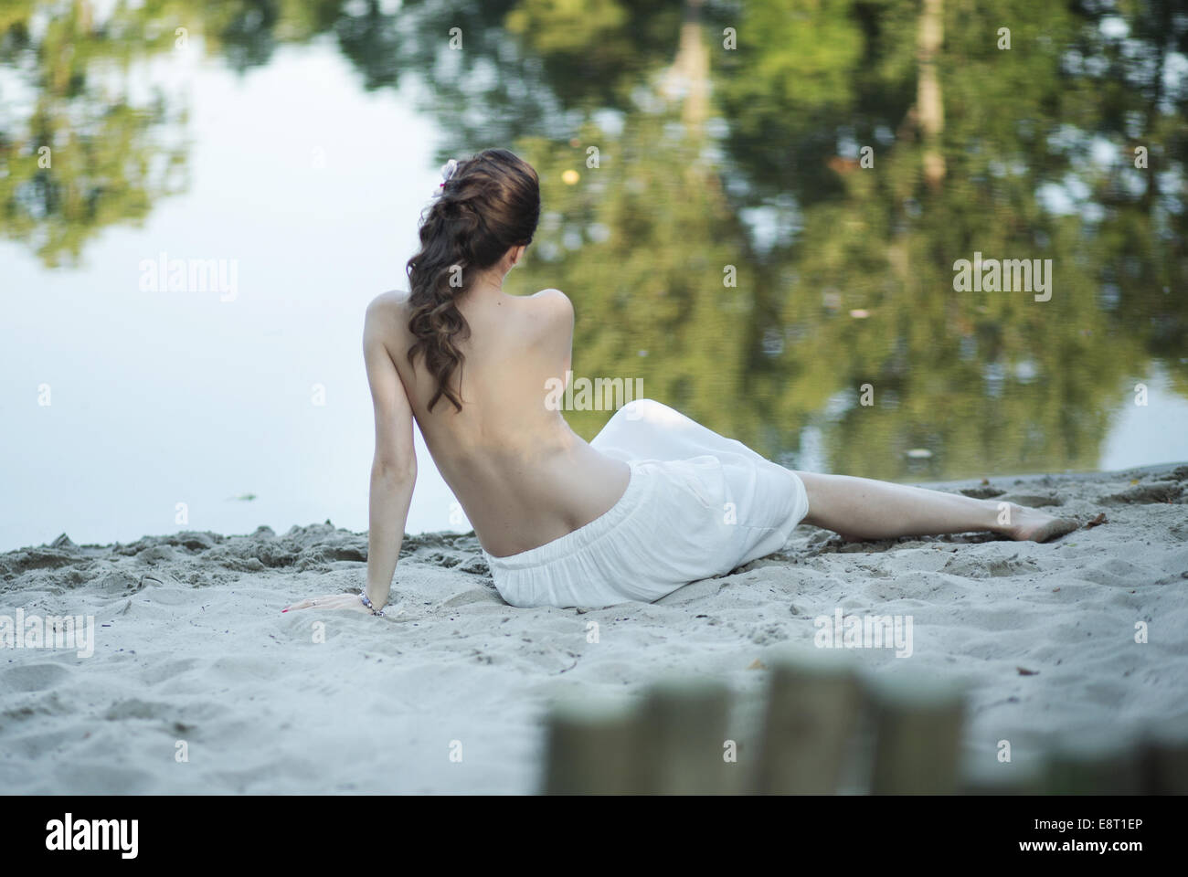 Moglie incinta sdraiato sulla spiaggia bianca Foto Stock