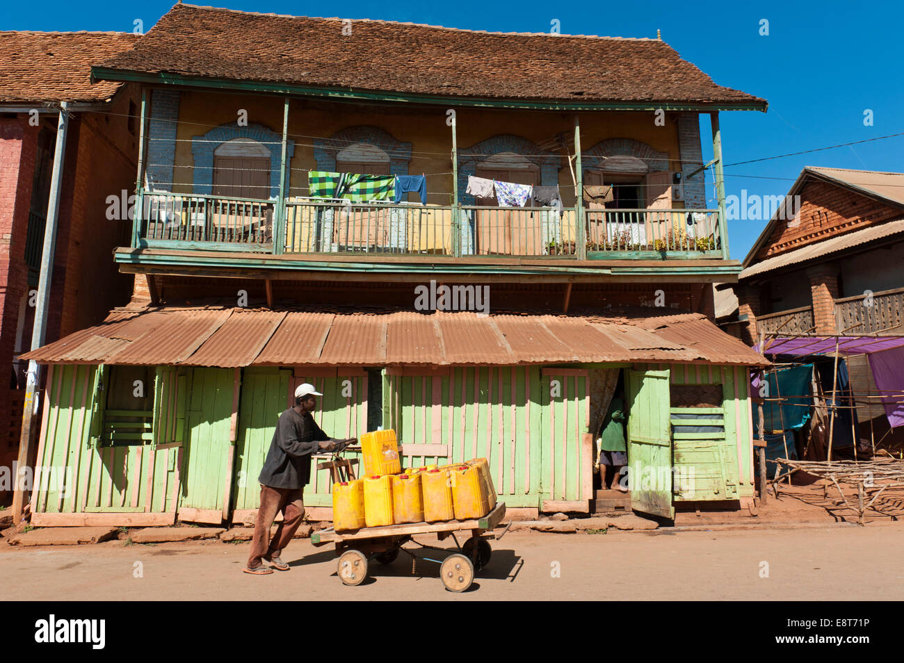 Uomo di spinta sulle merci fatta in casa carrello, architettura coloniale francese, Ambalavao, Madagascar Foto Stock