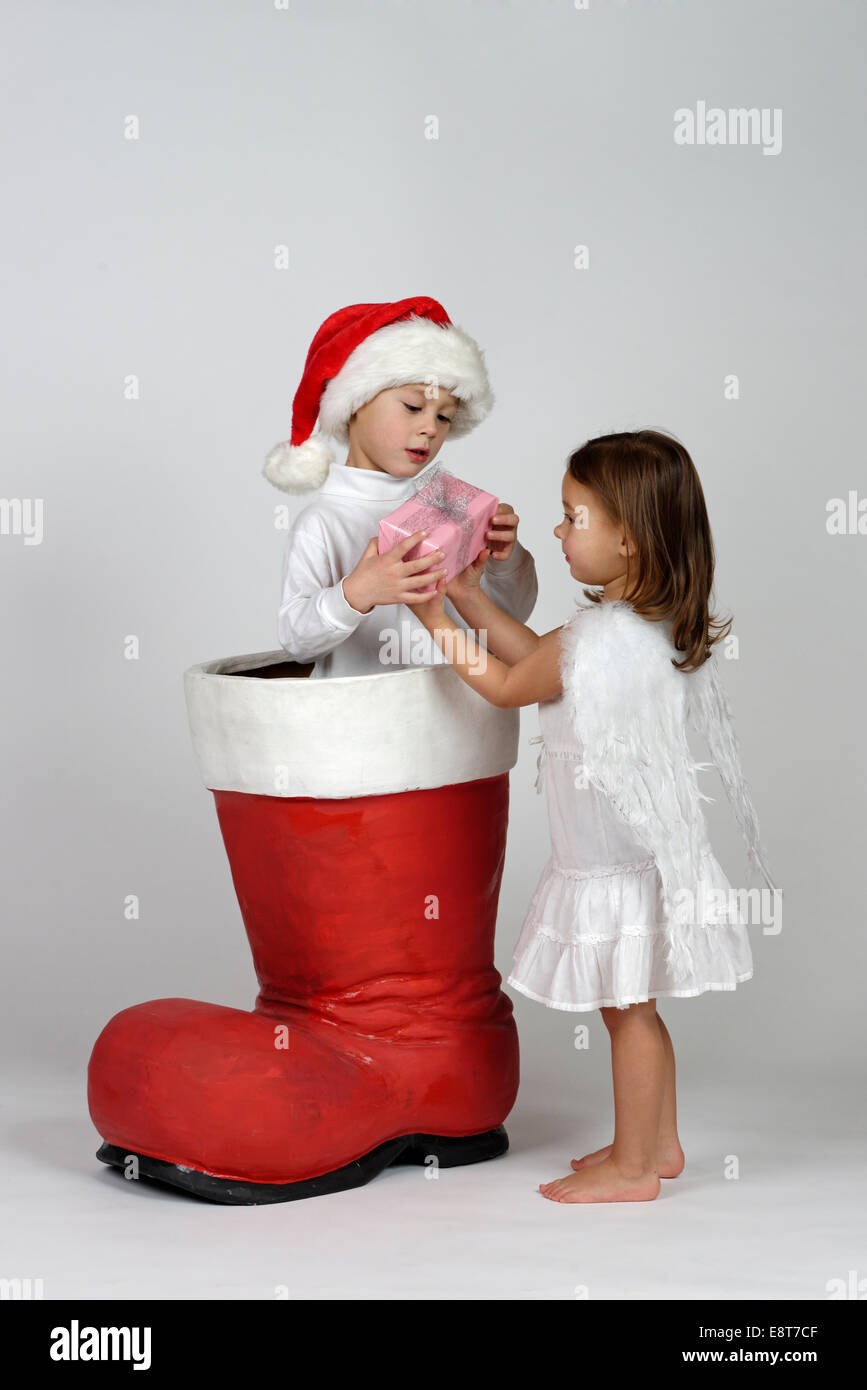 Ragazzo in un avvio di Natale di consegnare un piccolo regalo di Natale per una ragazza vestita come un angelo Foto Stock