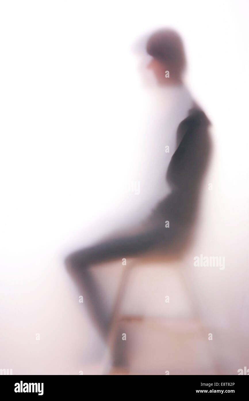 Silhouette di una donna seduta dietro un vetro smerigliato Foto Stock