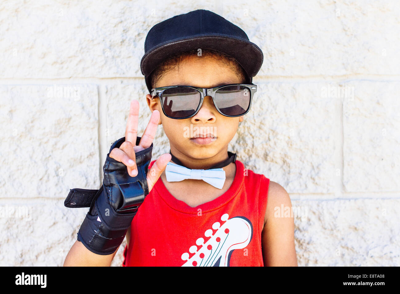 African American boy indossando il filtro bow tie, polsiera, occhiali da sole e cappello da baseball Foto Stock