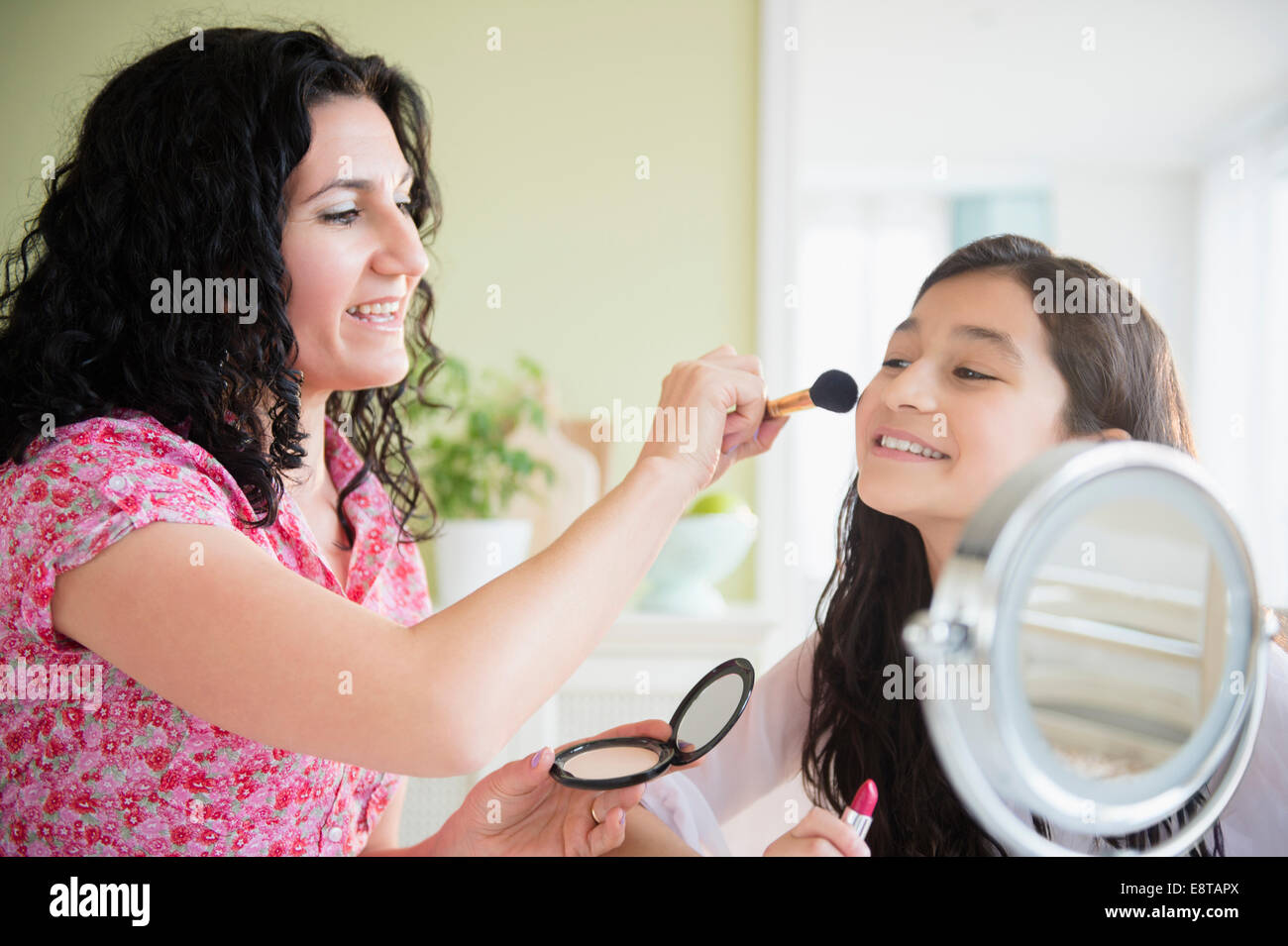 Madre ispanica aiutando la figlia applicare trucco Foto Stock