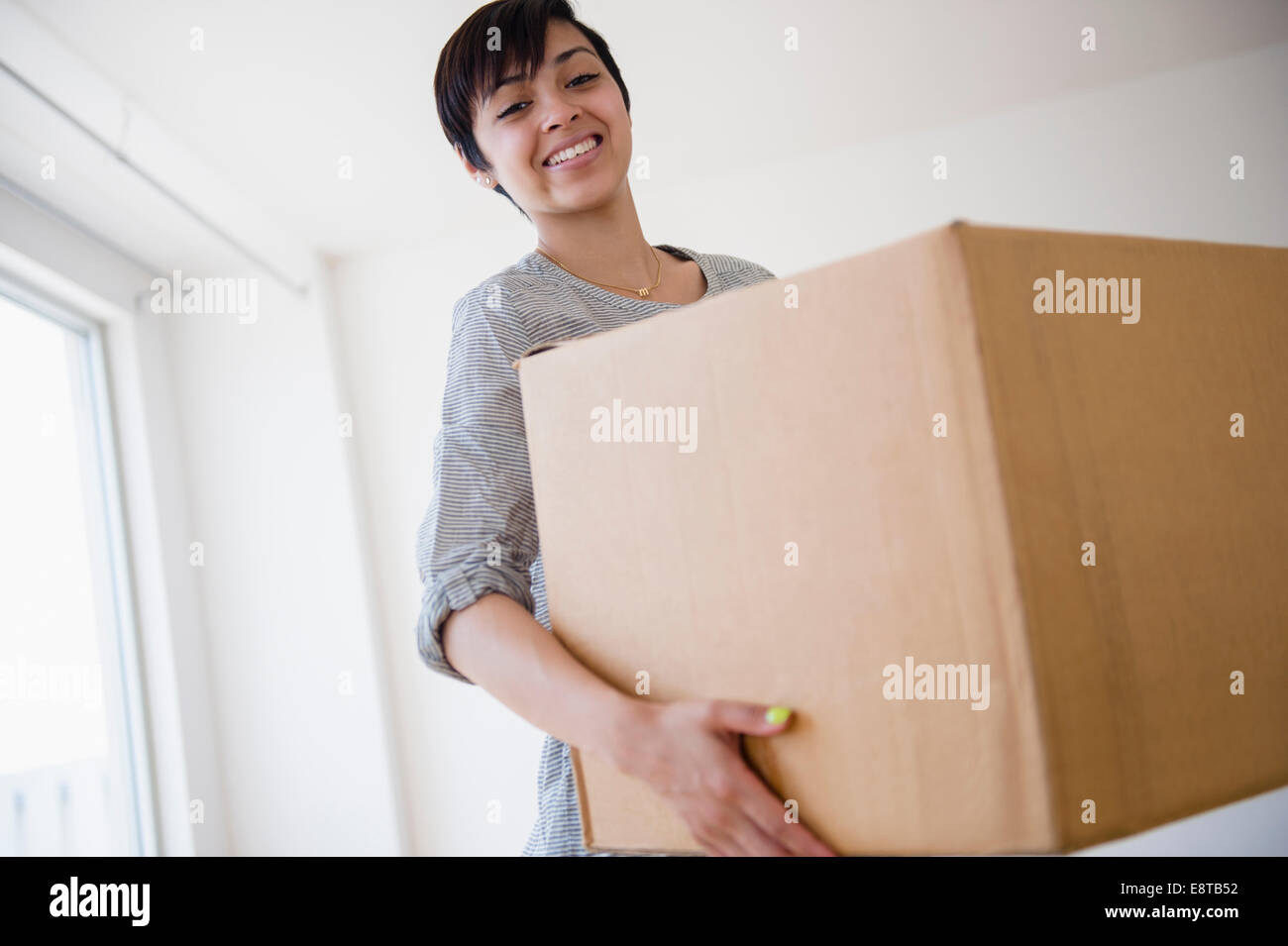 Sorridente razza mista donna trasportare la scatola di cartone Foto Stock