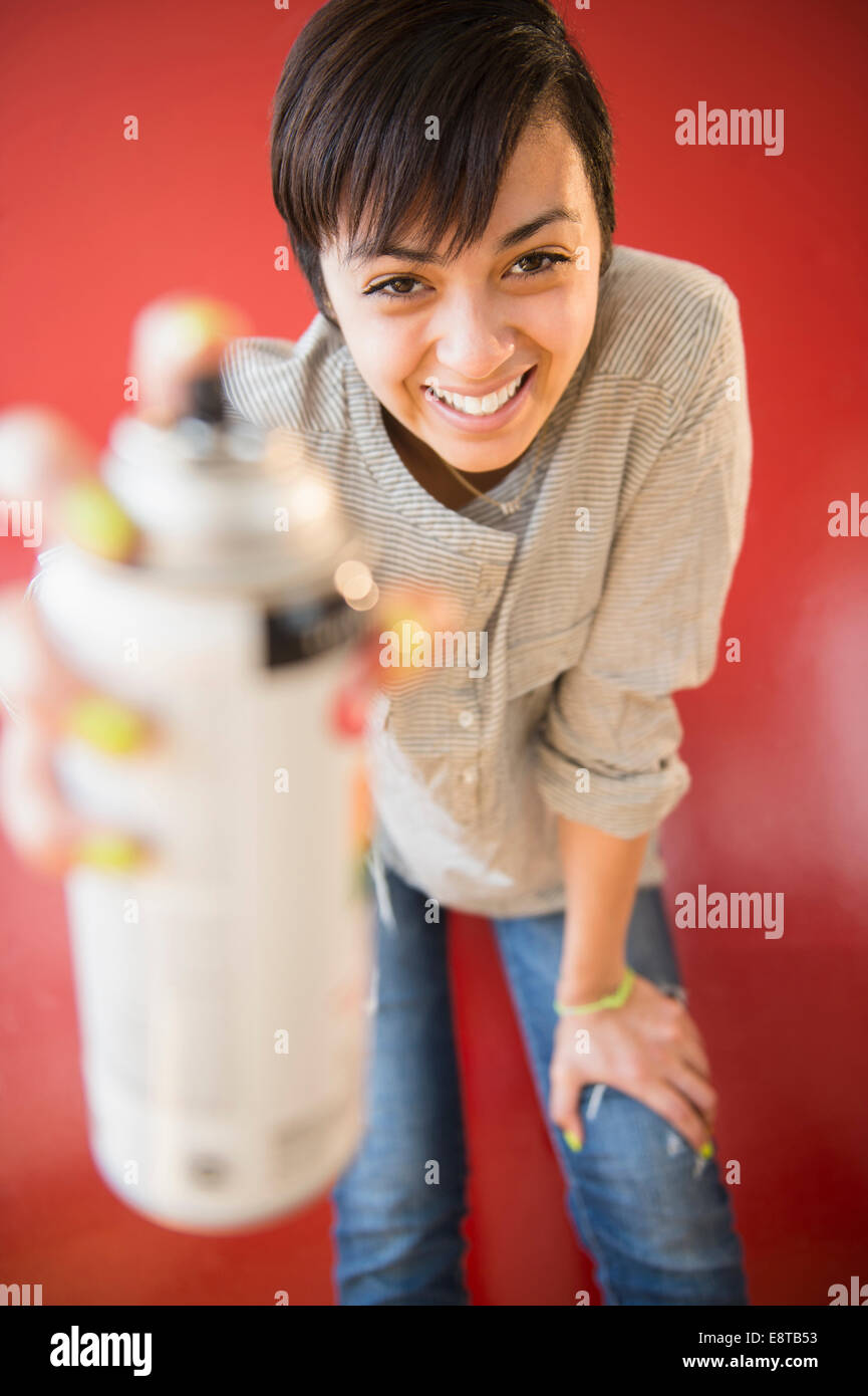 Sorridente razza mista donna holding bomboletta di vernice spray Foto Stock