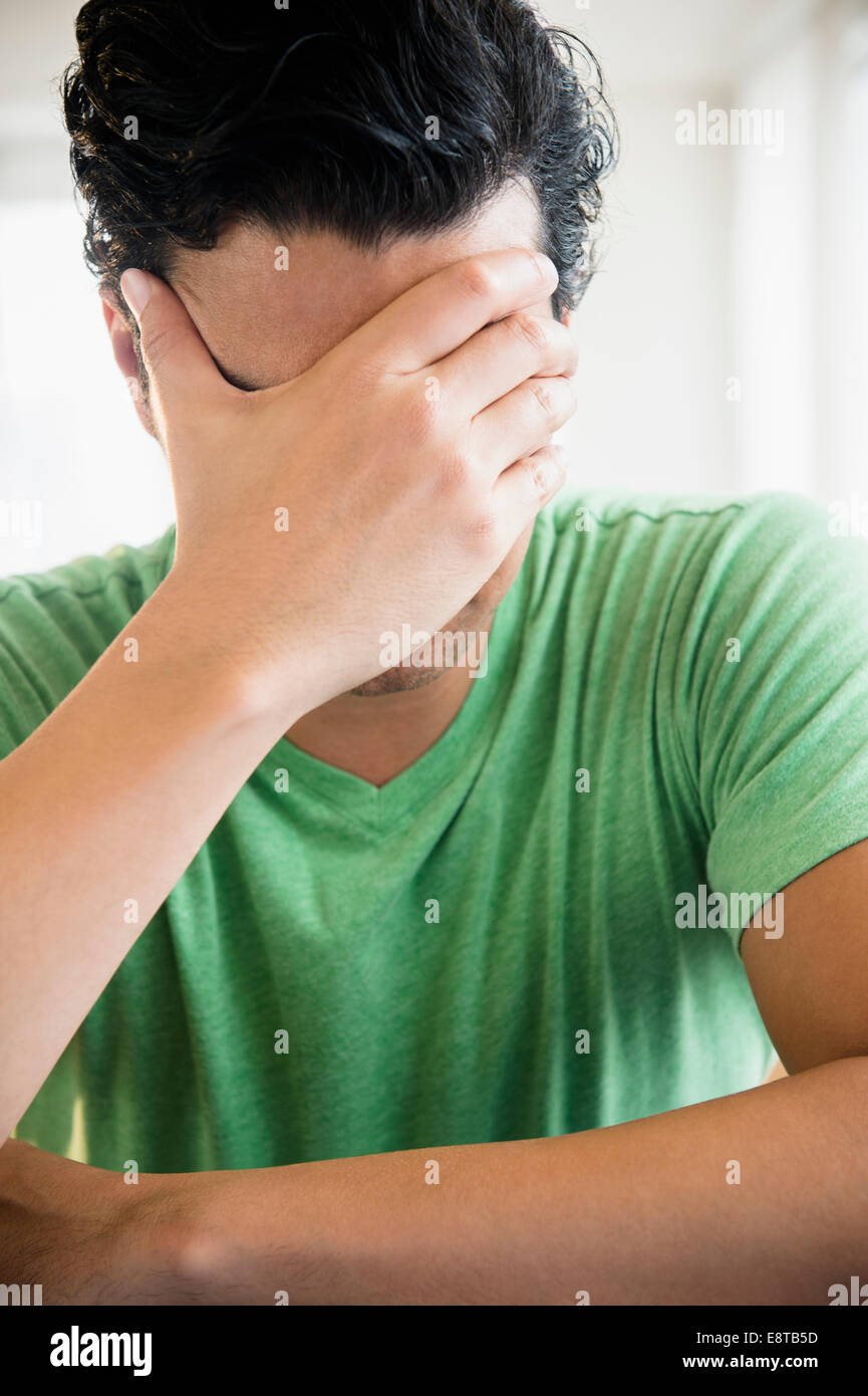 Frustrati razza mista uomo che copre il volto Foto Stock