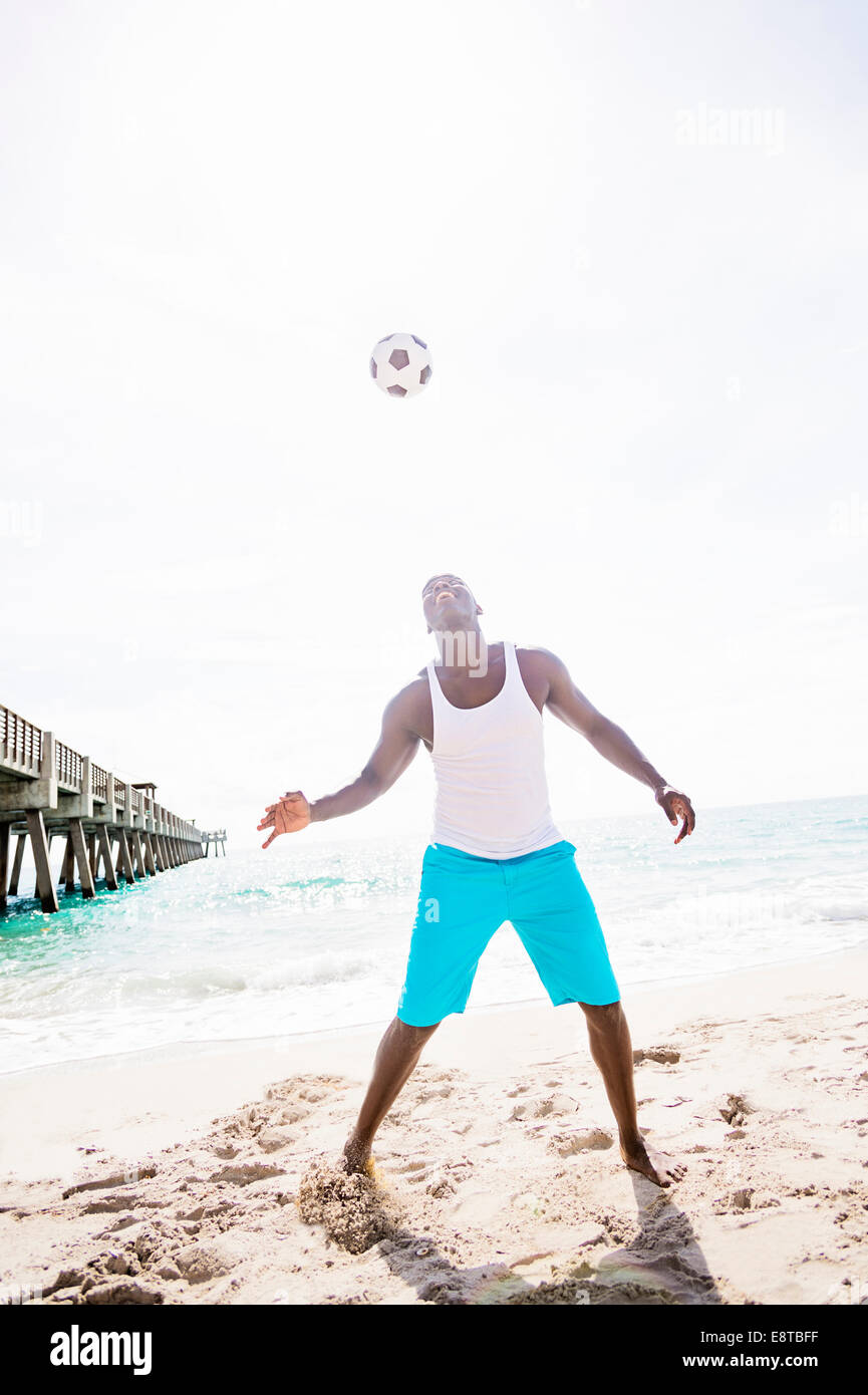 Razza mista uomo giocando con il pallone da calcio sulla spiaggia Foto Stock