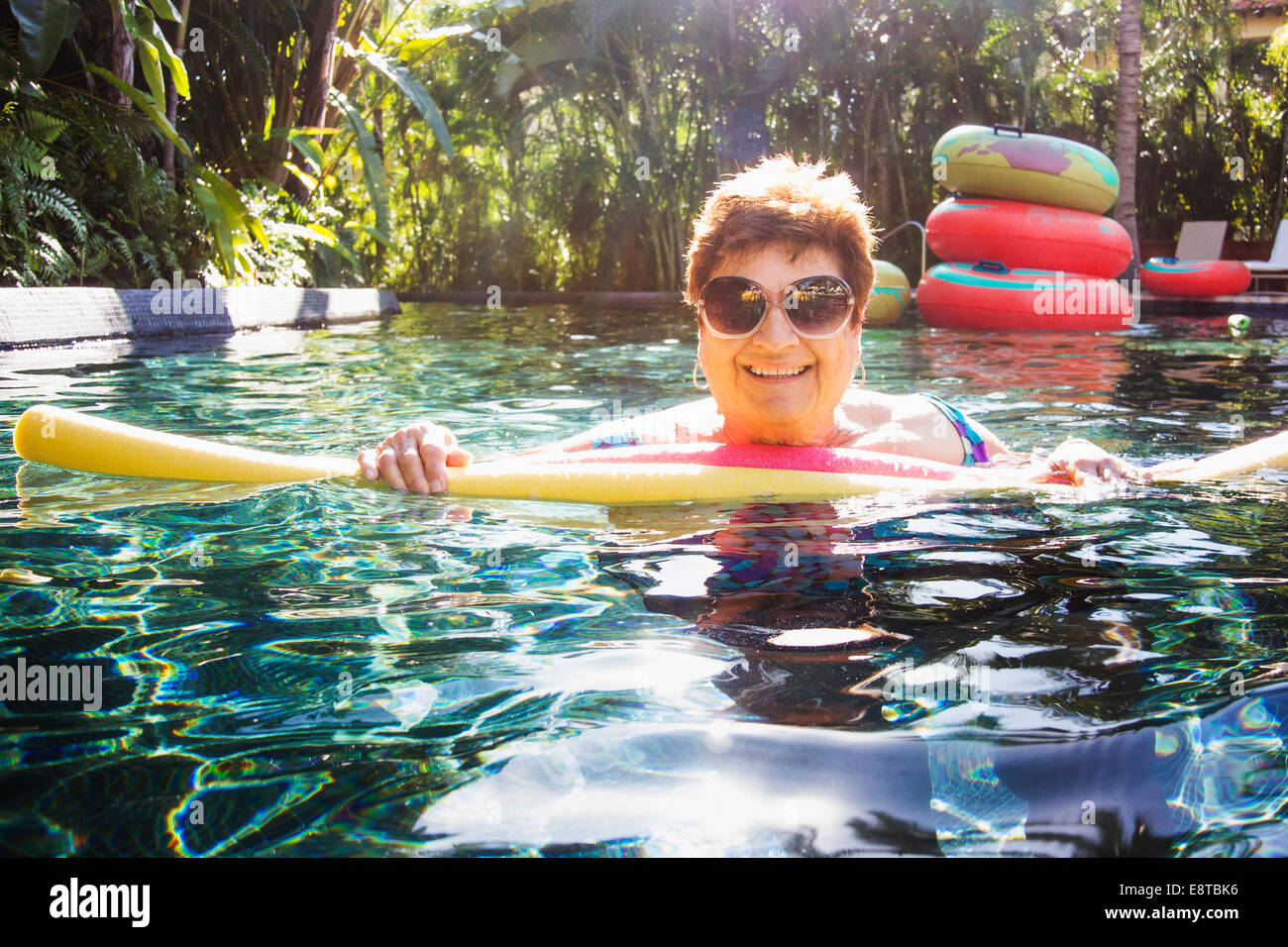 Donna anziana con occhiali da sole in piscina Foto Stock