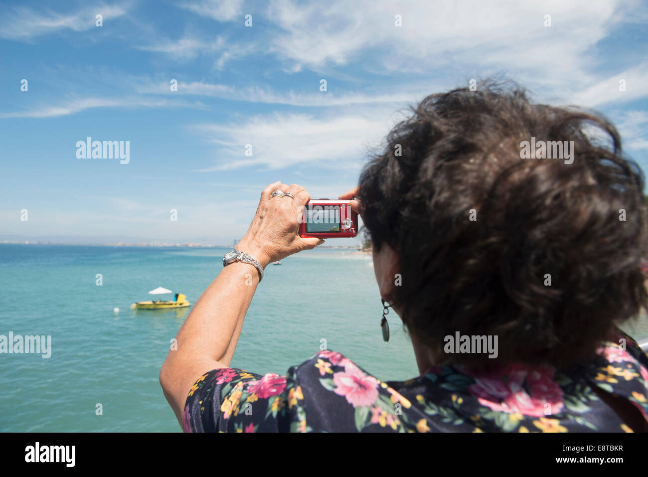 Donna anziana tenendo fotografia di oceano tropicale Foto Stock