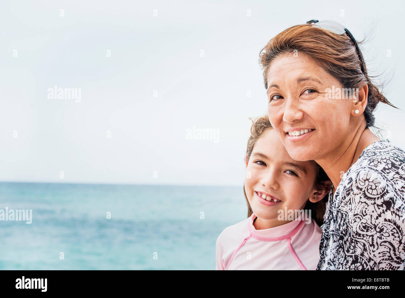 Asian madre e figlia sorridenti vicino oceano Foto Stock