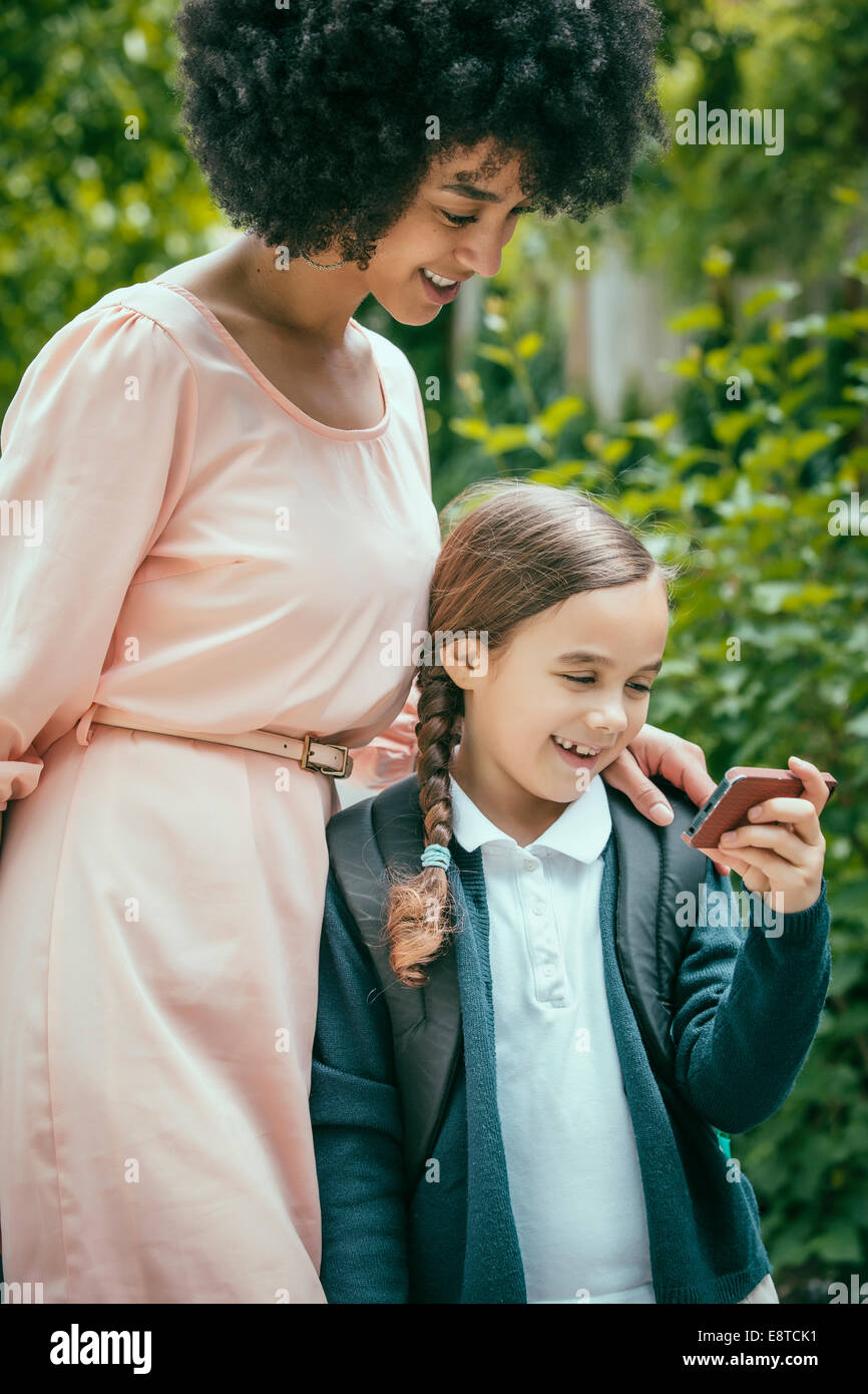 Razza mista madre e figlia tramite telefono cellulare insieme Foto Stock