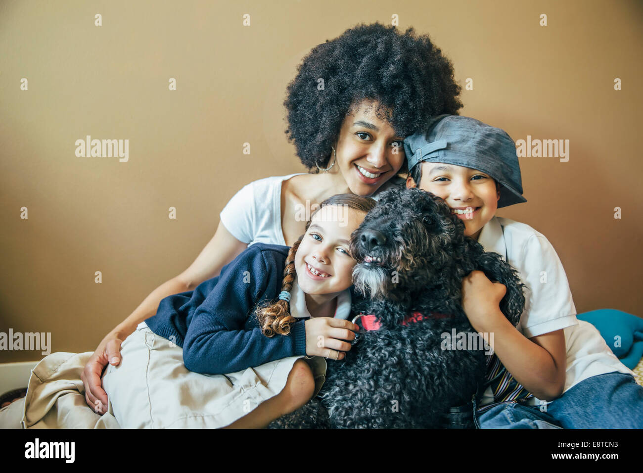 Razza mista madre e bambini abbracciando il cane Foto Stock