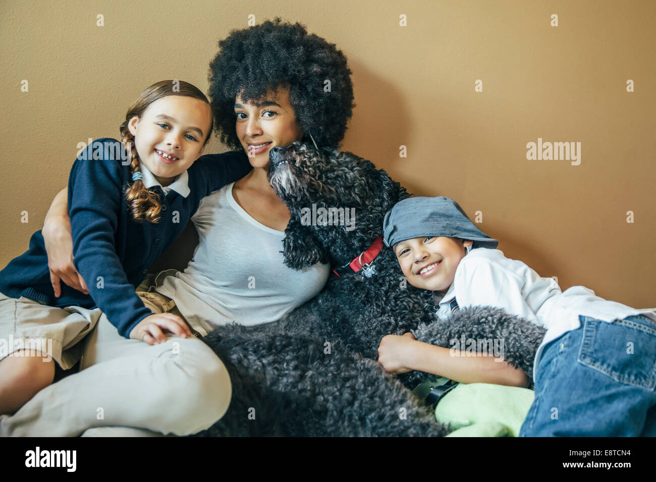 Razza mista madre e bambini abbracciando il cane Foto Stock