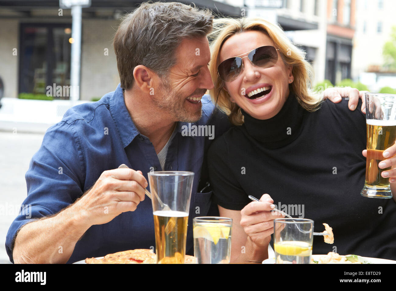Coppia caucasica bere e mangiare al cafè sul marciapiede Foto Stock