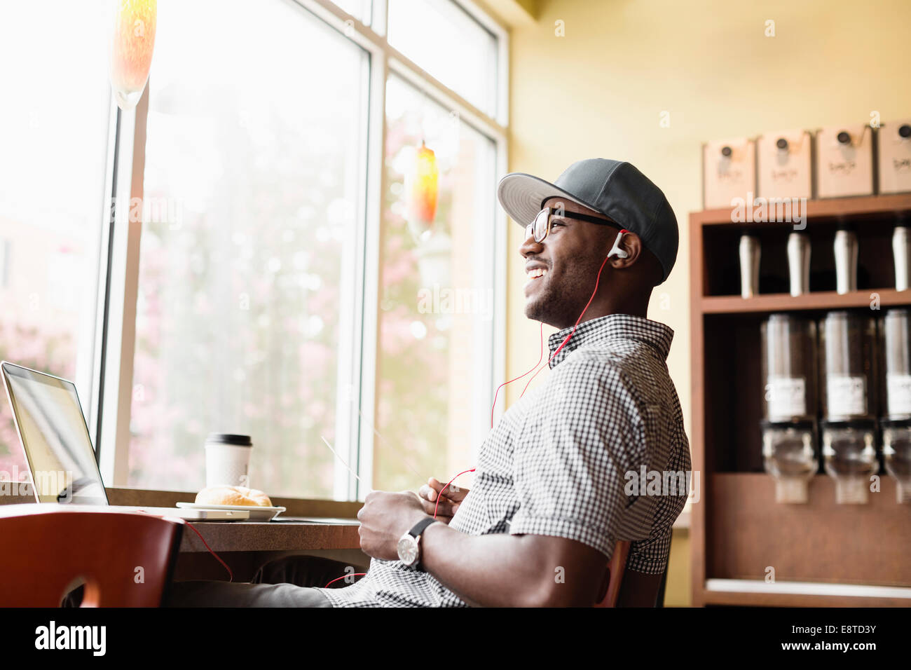 Ridendo uomo nero utilizzando laptop in coffee shop Foto Stock