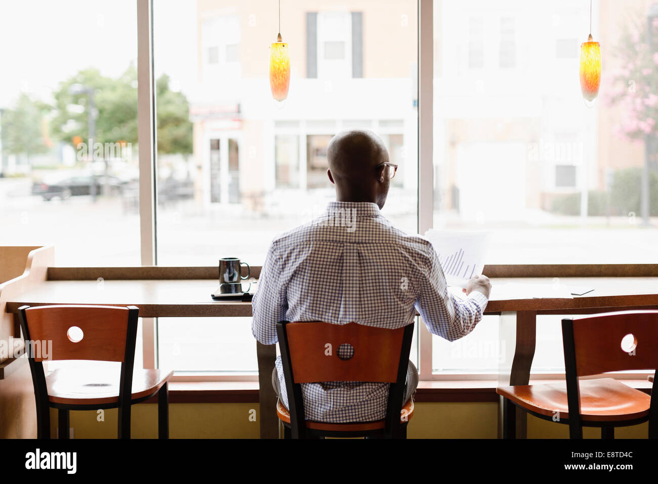 Uomo nero leggendo la documentazione in coffee shop Foto Stock