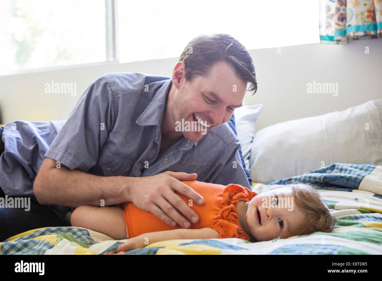 Padre caucasica giocando con la figlia sul letto Foto Stock