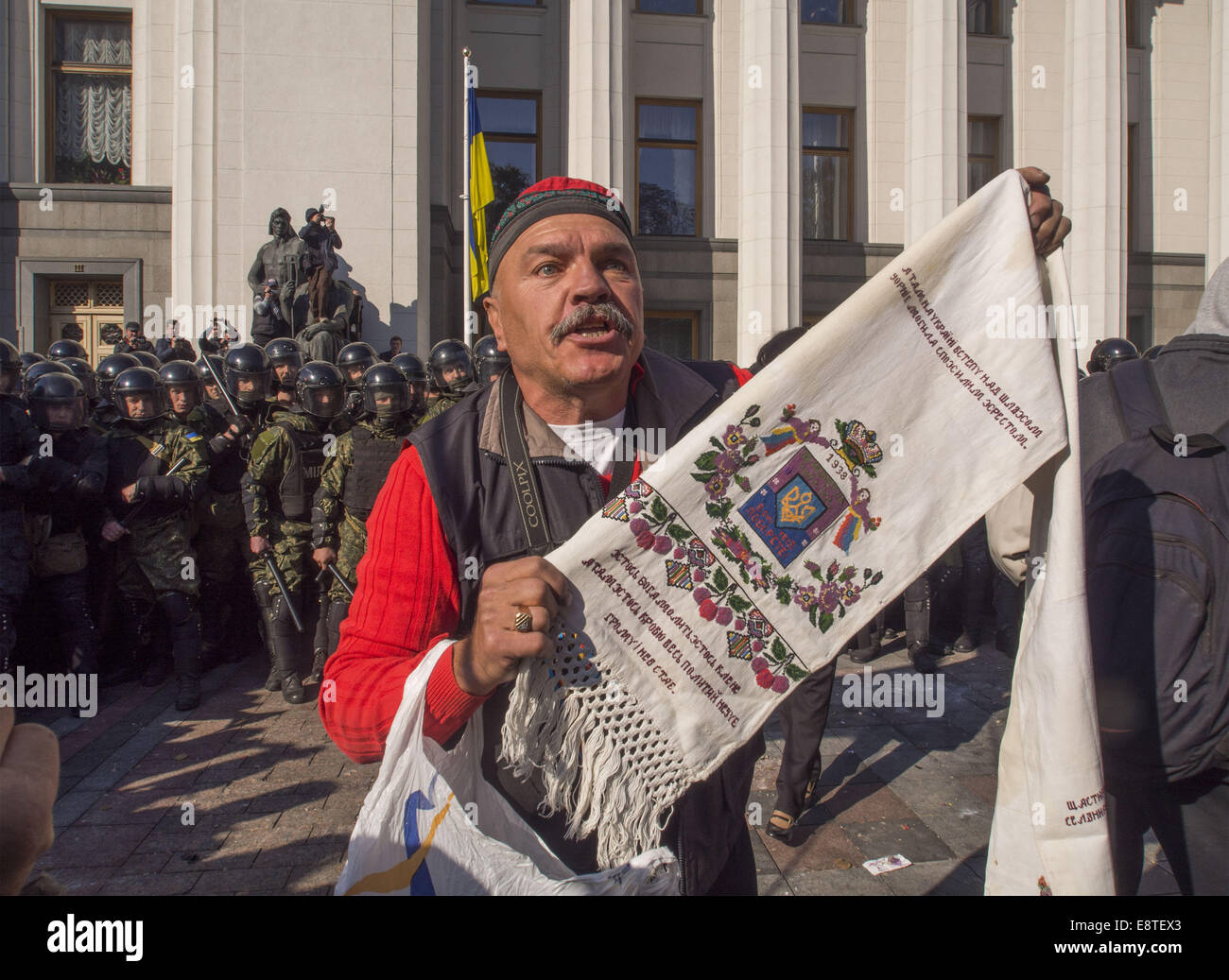 L'uomo con l'asciugamano ricamato si erge tra i radicali e le forze di polizia per impedire una collisione. Xiv oct, 2014. -- ''Settore DESTRO'' e ''libertà'' disown provocazioni alla Verkhovna Rada. Una trentina di manifestanti ha iniziato a lanciare i soldati della guardia nazionale acciottolato presso l'edificio della Verkhovna Rada. I manifestanti hanno chiesto la messa al bando del partito comunista e il riconoscimento dell'Ucraina esercito di insorti belligerante nella II Guerra Mondiale. © Igor Golovniov/ZUMA filo/Alamy Live News Foto Stock