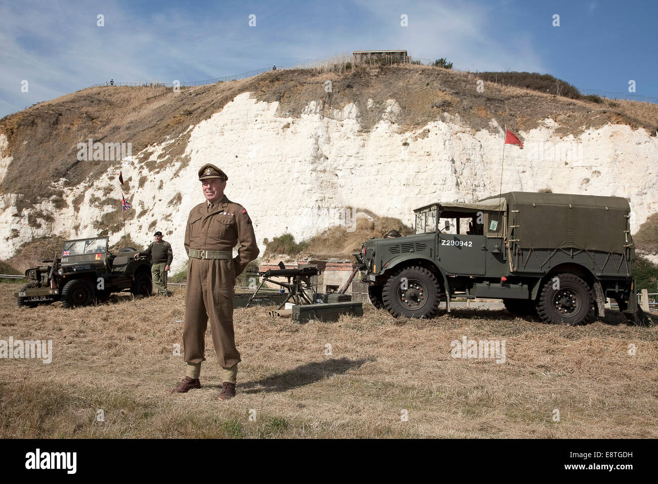 Seconda guerra mondiale veterani dell esercito / reenactors. in piedi con le armi e veicoli in font di scogliere bianche a Newhaven, Sussex Foto Stock