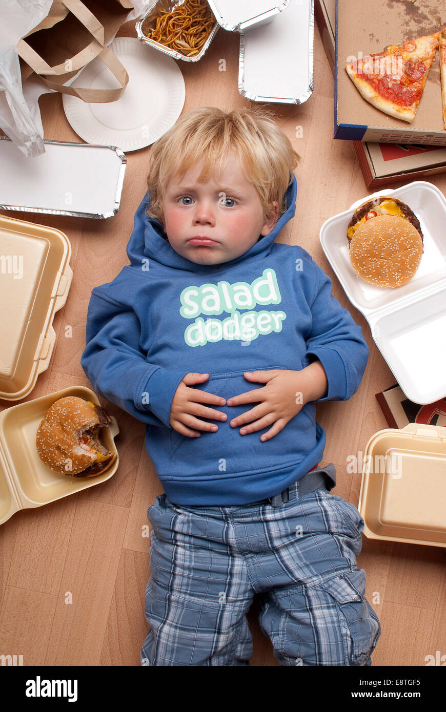 Bambino sulla commedia colpo di sfondo in un studio di indossare abbigliamento fresco con fast food, cibo spazzatura, hamburger, omaggio, Foto Stock