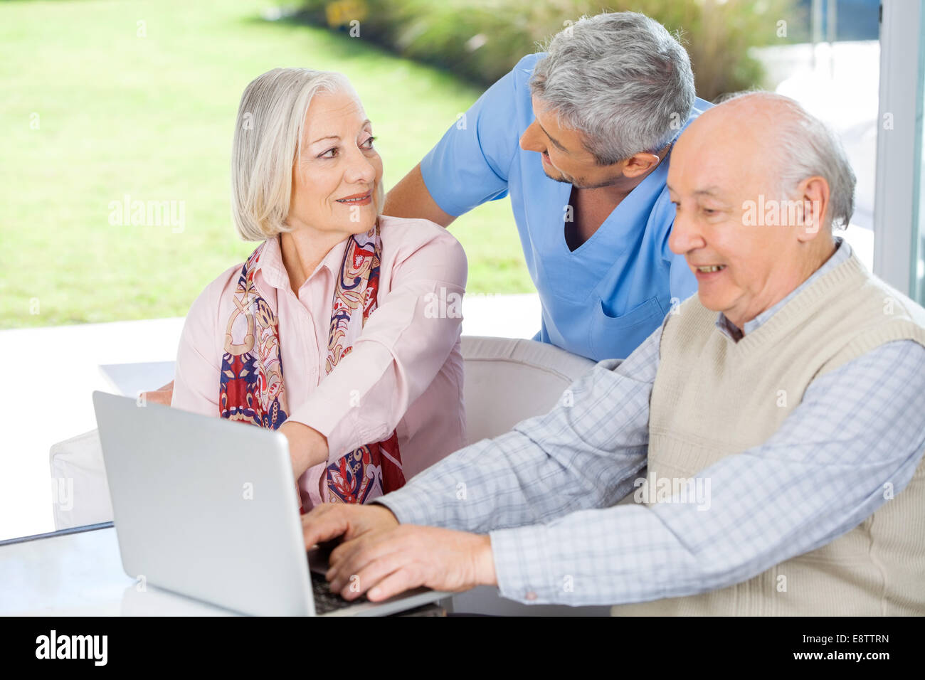 Custode Guardando Senior donna da Uomo con laptop Foto Stock
