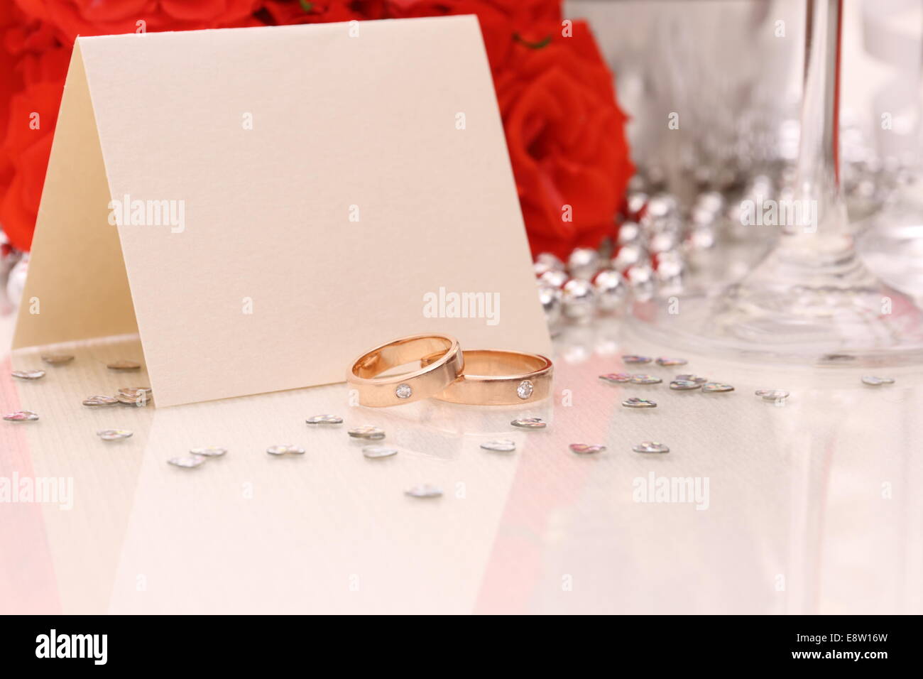 Due golden gli anelli di nozze con carta, champagne e rose rosse Foto Stock