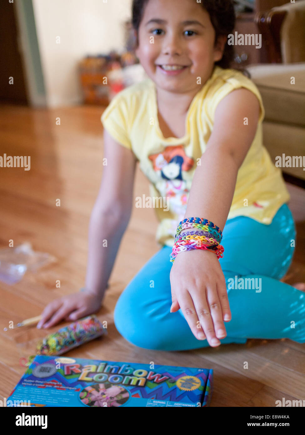 Un grazioso piccolo ragazza mostra il suo colorato Rainbow telaio braccialetti. Foto Stock