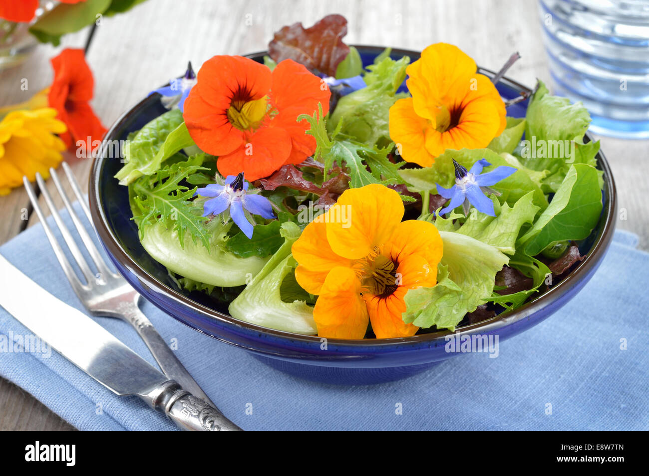 Fresca Insalata estiva con fiori commestibili i nasturzi, borragine fiori in un vaso. Foto Stock