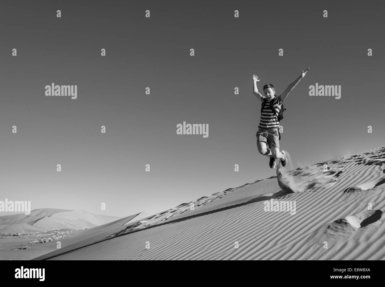 Adolescente di salto e correre giù per una duna a Sossusvlei, Namib Desert, Namibia Foto Stock