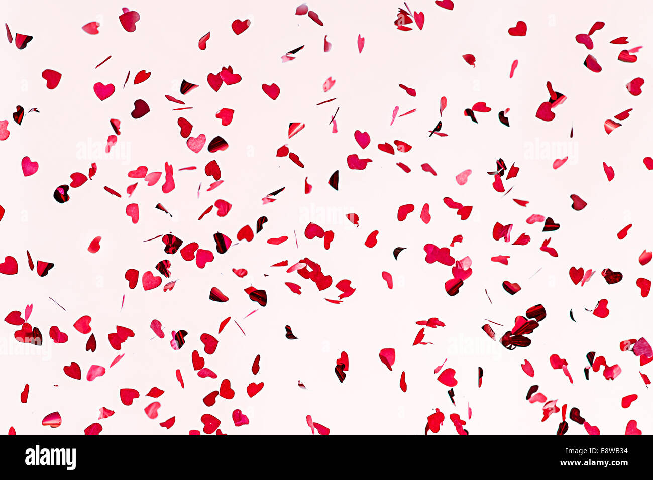 Tutto ciò di cui hai bisogno è l'amore. Vista ingrandita di coriandoli cuori di colore rosso contro lo sfondo di colore rosa. Foto Stock