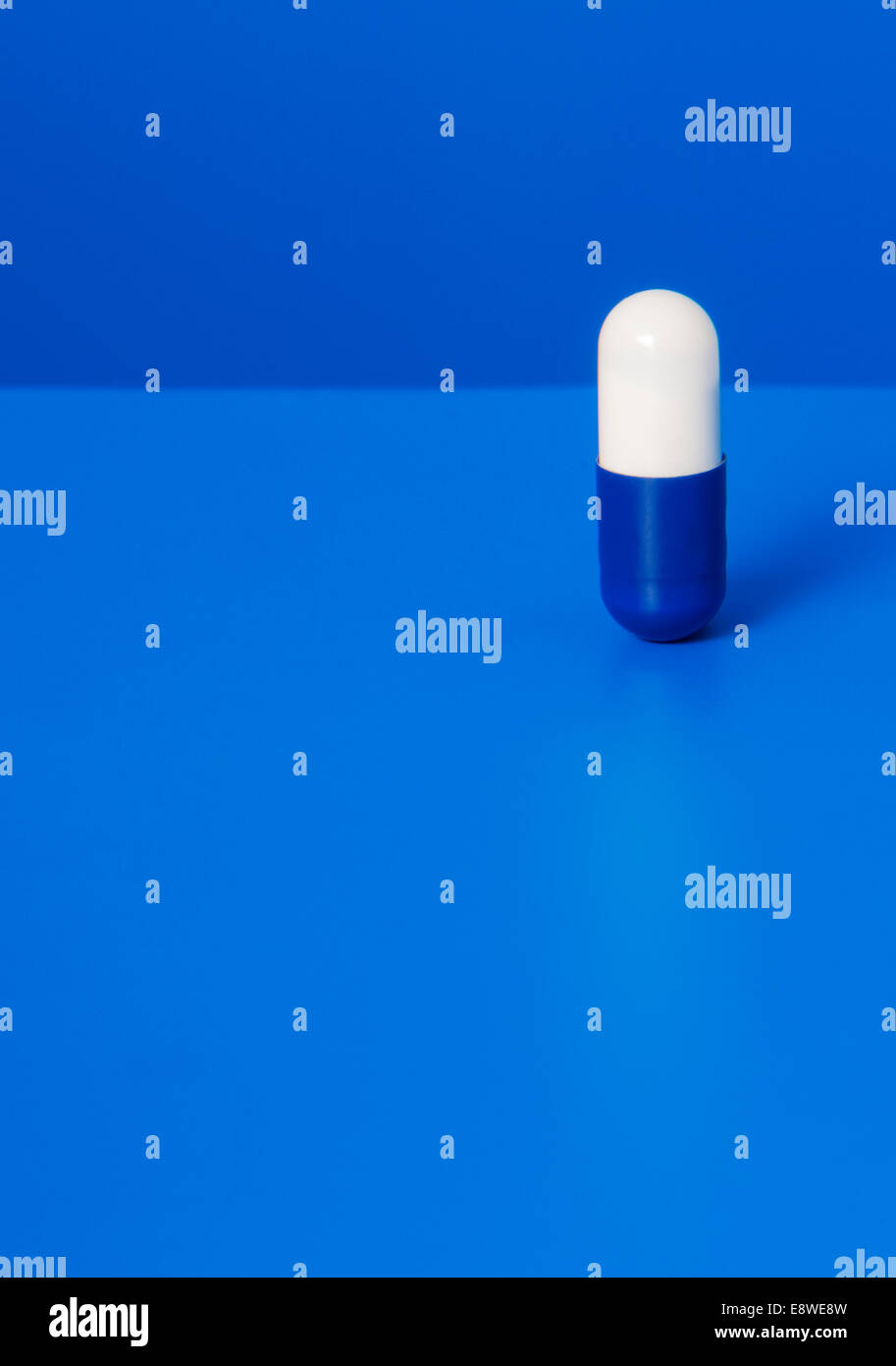 Ravvicinata di una pillola di prescrizione su sfondo blu Foto Stock