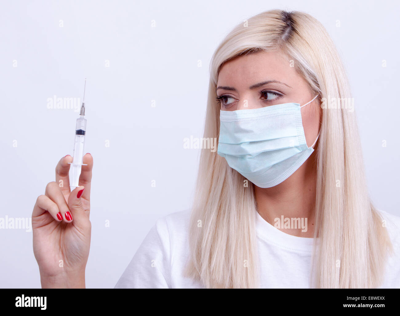 Donne medico o infermiere in maschera medico tenendo la siringa di iniezione Foto Stock