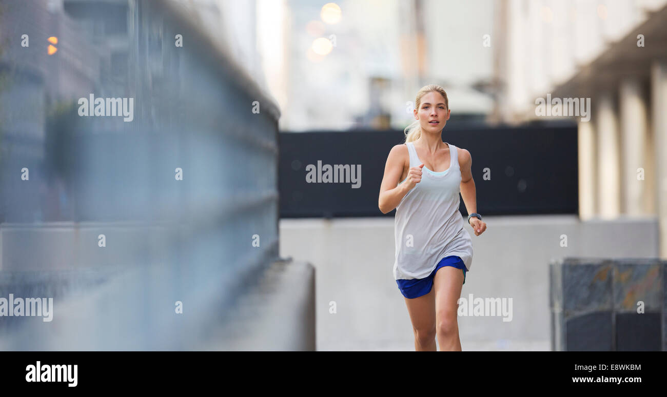 Donna che corre attraverso le strade della città Foto Stock