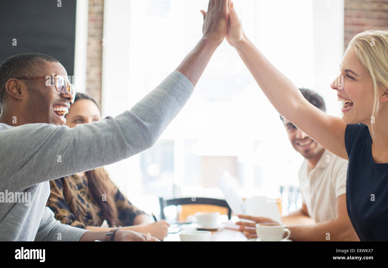 La gente di affari ad alta fiving alla riunione in cafe Foto Stock