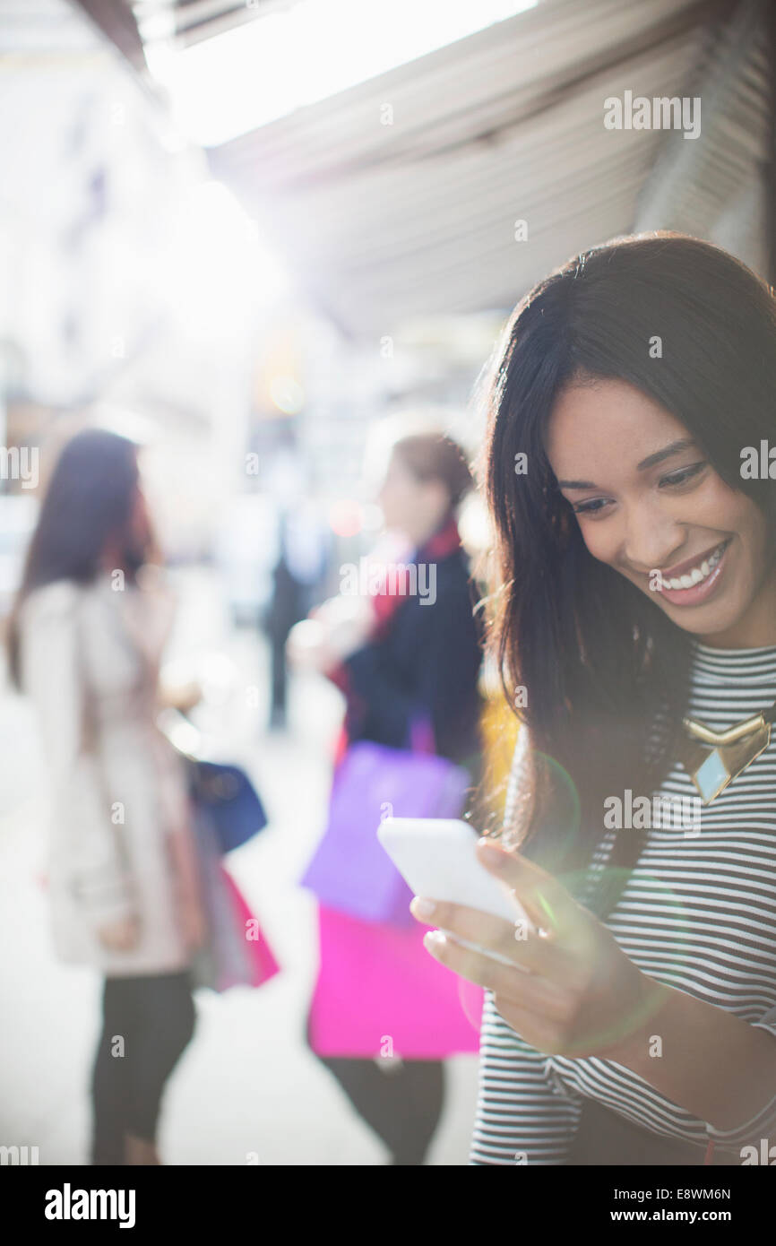 Donna che utilizza il telefono cellulare su una strada di città Foto Stock