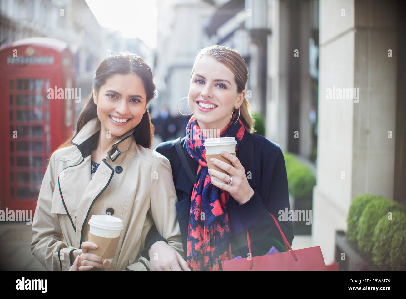 Le donne di bere caffè insieme lungo una strada di città Foto Stock