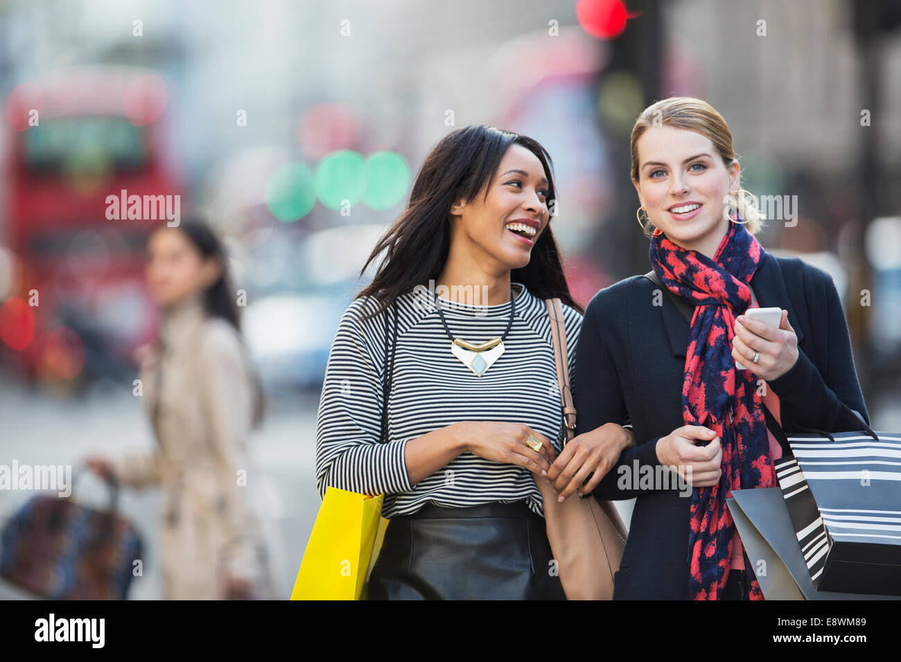Donne in cammino insieme lungo una strada di città Foto Stock