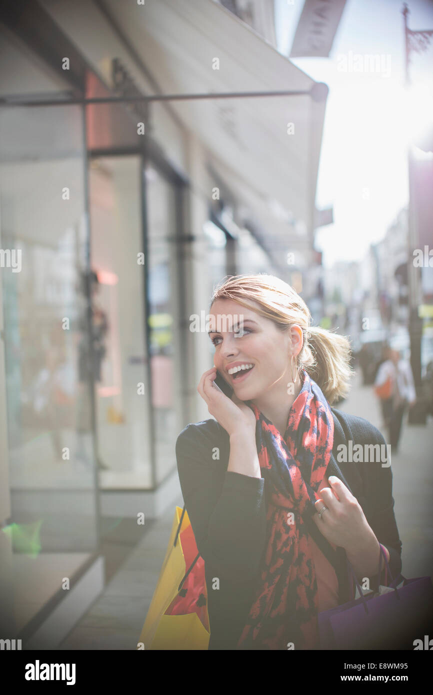 Donna che parla al cellulare mentre si cammina lungo una strada di città Foto Stock