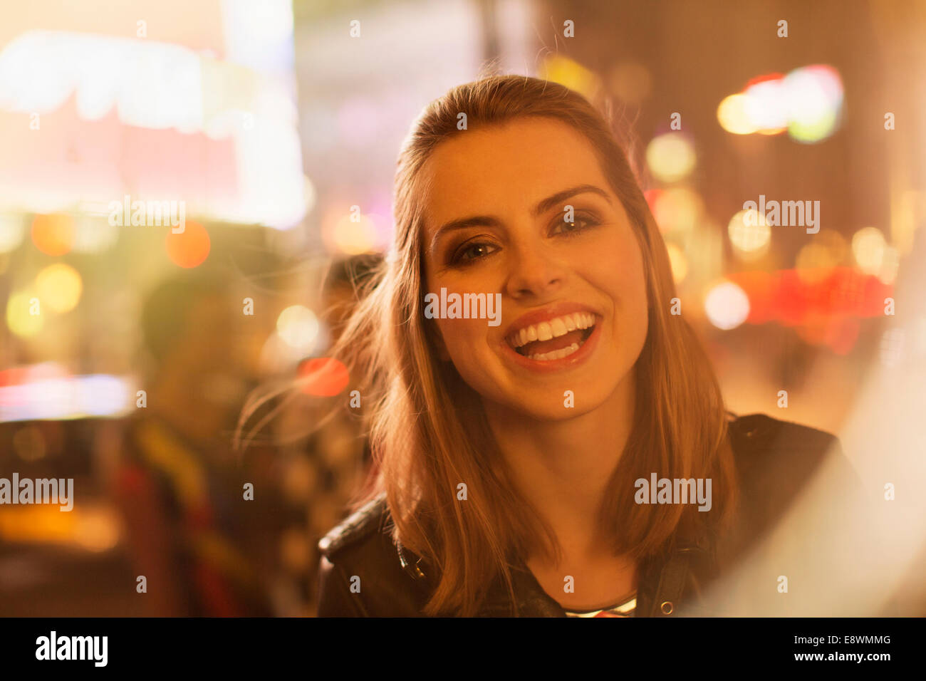 Donna sorridente su una strada di città di notte Foto Stock