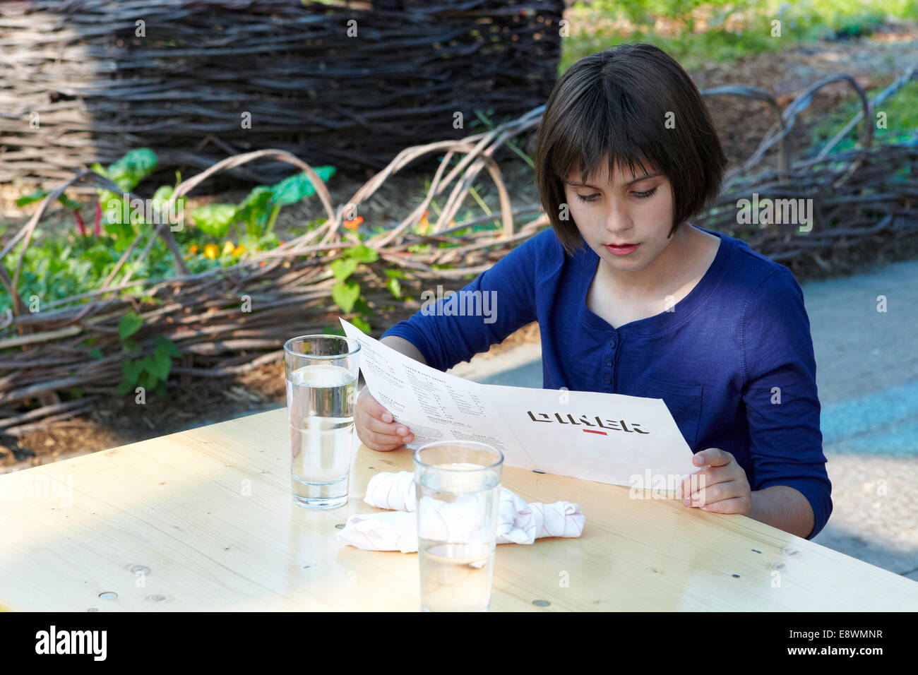 11 anno vecchia ragazza guardando il menu del ristorante Foto Stock