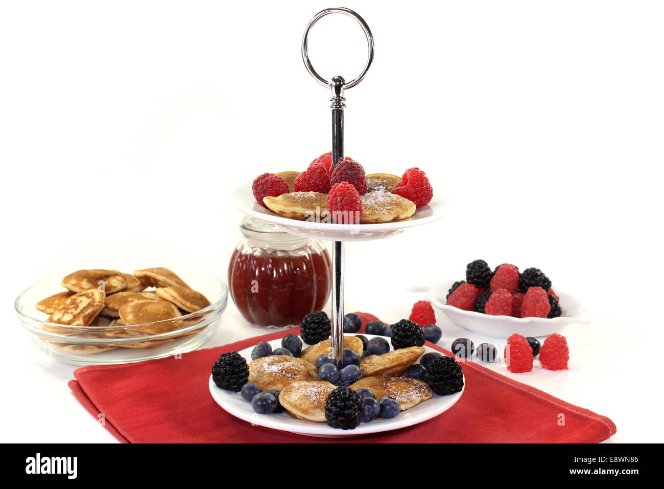 Poffertjes con lamponi e mirtilli su una torta di stand Foto Stock