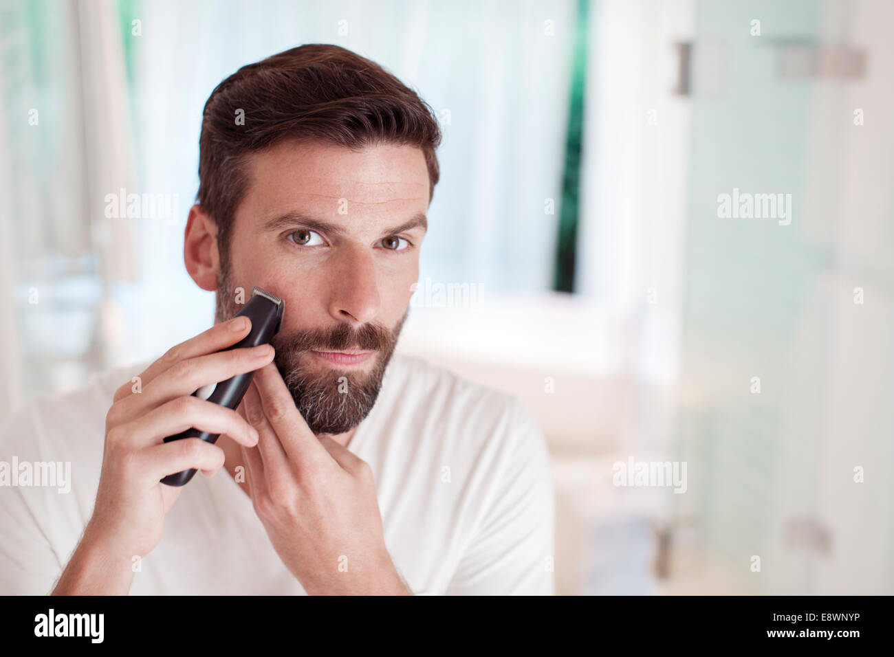 Uomo barba di trimming nello specchio del bagno Foto Stock