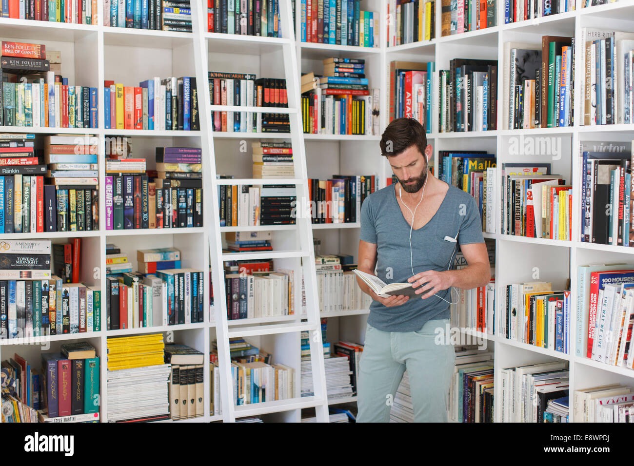Uomo che ascolta la musica in libreria Foto Stock