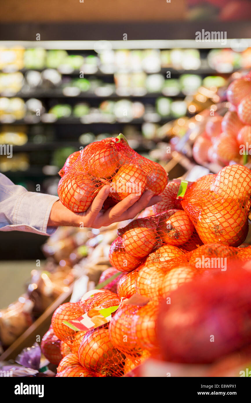 Close up uomo sacco di contenimento di cipolle in negozio di alimentari Foto Stock