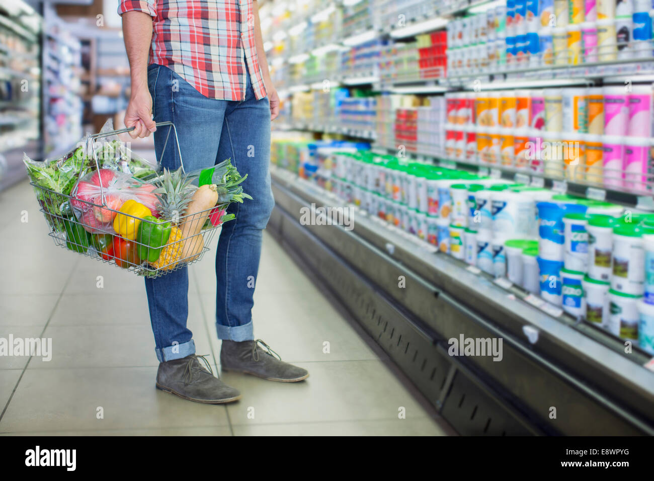 Uomo che porta la piena Shopping basket in negozio di alimentari Foto Stock