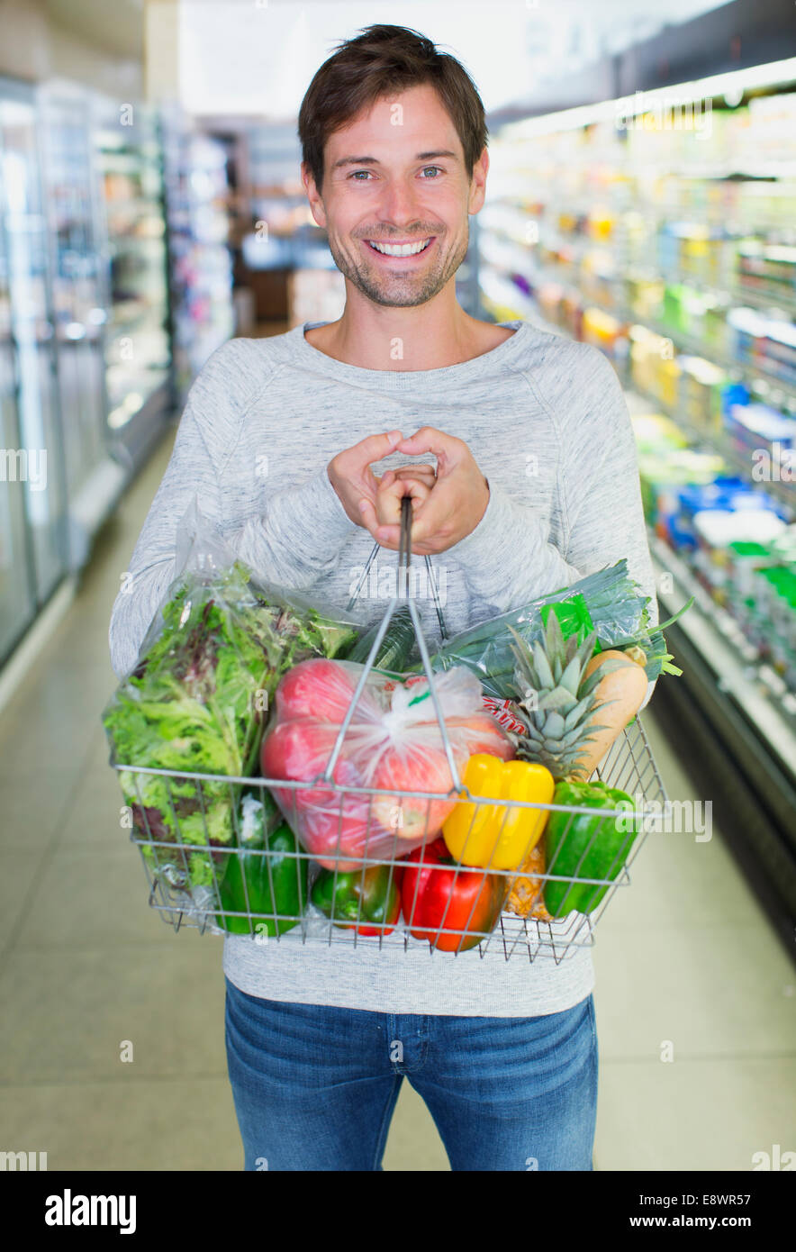 Uomo con piena Shopping basket in negozio di alimentari Foto Stock