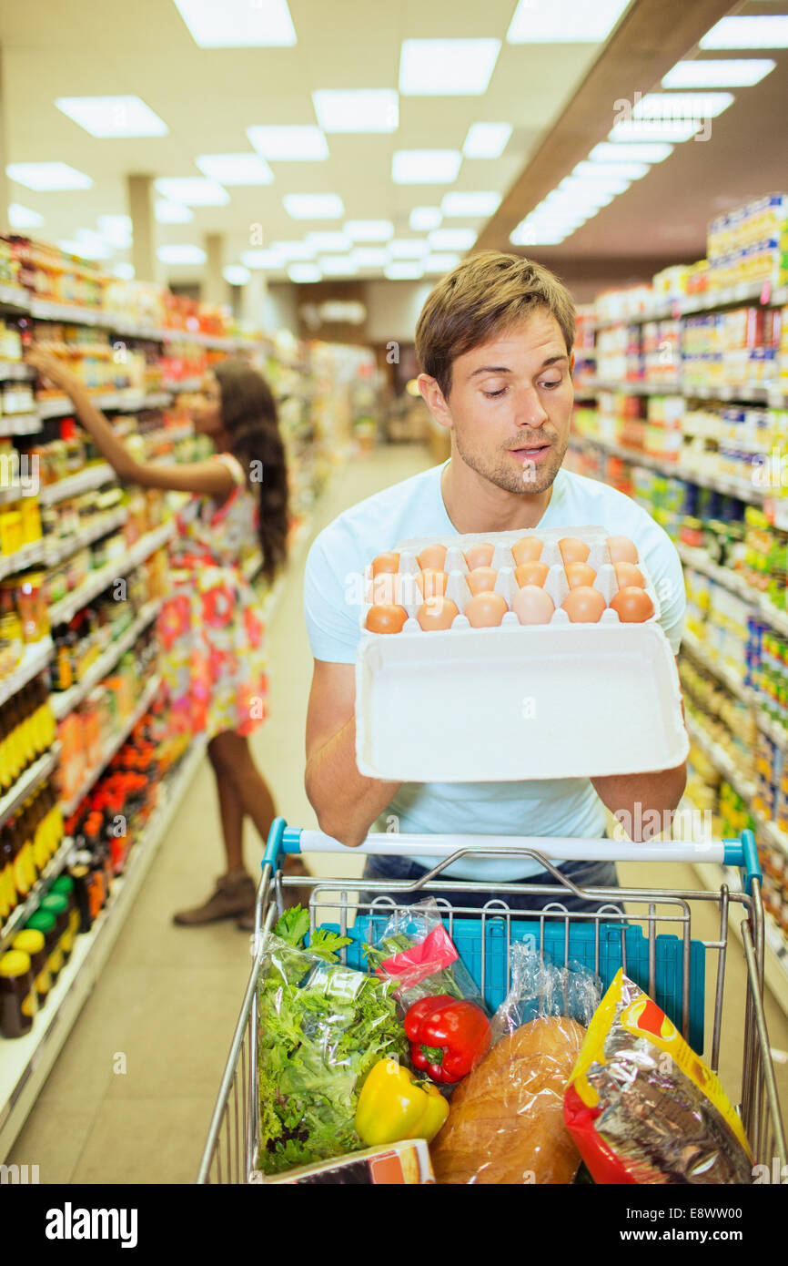 L'uomo esame di cartone di uova nel negozio di alimentari Foto Stock