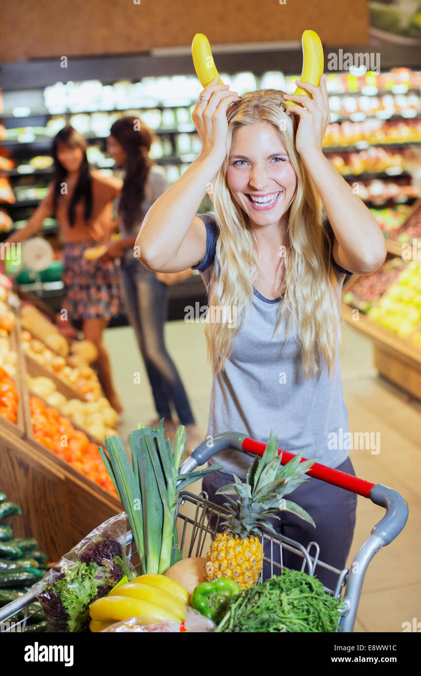 Donna che gioca con le banane mentre lo shopping nel negozio di alimentari Foto Stock